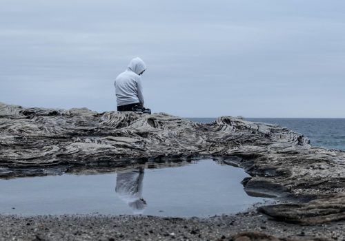 sitting by self in hoodie on rocks